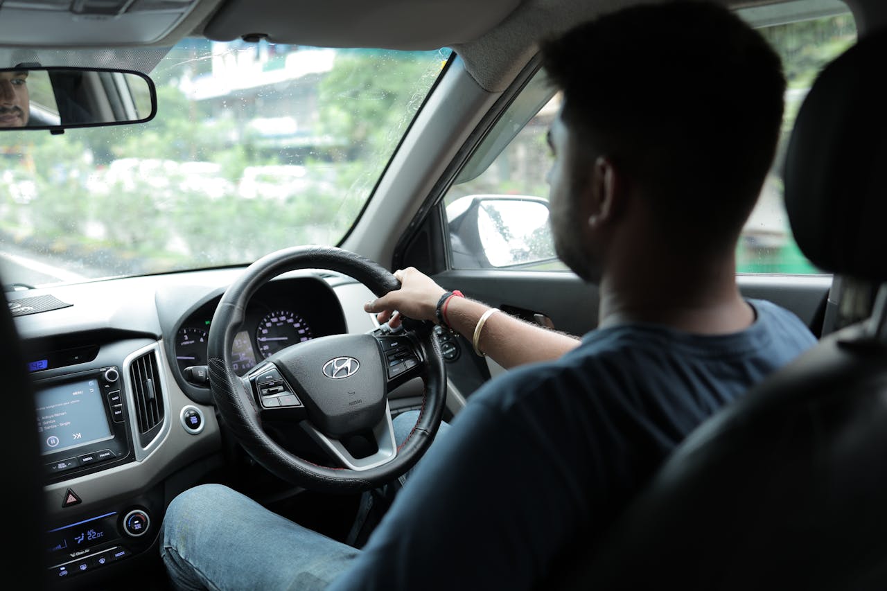 View from the passenger seat showing a man driving, focusing on the car's interior and road ahead.